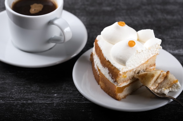 Foto stück kuchen mit sanddorn auf einem teller mit einer tasse kaffee auf