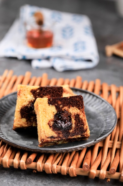 Stück Marmor Reisekuchen, quadratischer Kuchen mit geschmolzener Schokolade in der Mitte. Auf rustikalem Teller serviert