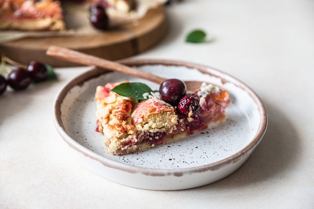 Stück offene Torte oder Galette mit Kirsch-, Mandel- und Vanilleeis, heller Hintergrund.