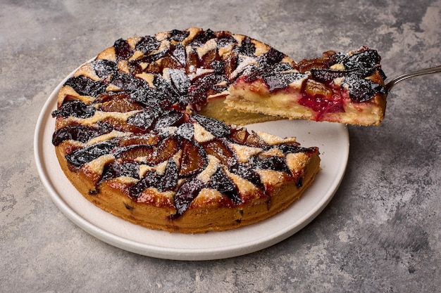 Foto stück pflaumenkuchen auf dem schulterblatt und kuchen auf dem teller, nahaufnahme, selektiver fokus