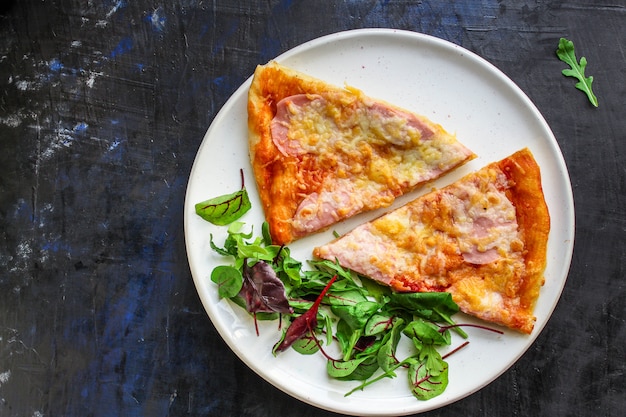 Stück Pizza und Salatblätter in einem Teller