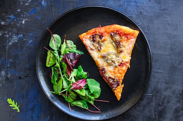 Stück Pizza und Salatblätter in einem Teller