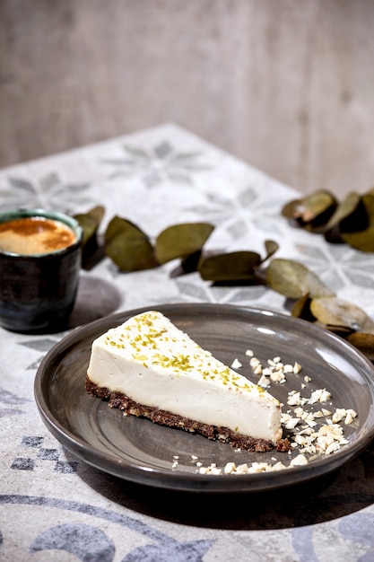 Stück roher veganer Käsekuchen, kein Backen glutenfrei, dekoriert mit Limettenschale und Cashewnüssen auf Teller