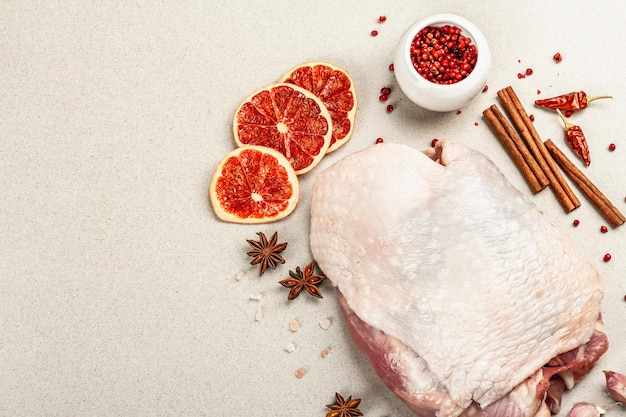 Stück rohes Putenfleisch mit Gewürzen. Eine nützliche Zutat für die Zubereitung gesunder Lebensmittel, Gewürze, Knoblauch. Steinbetonhintergrund, Draufsicht