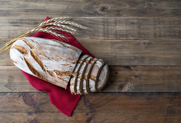 Stück rustikales Brot auf Holzhintergrund mit Verzierungen von Ähren Kopieren Sie Platz