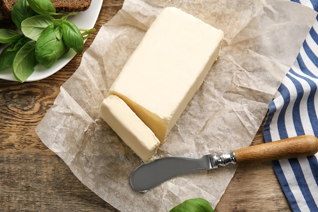 Stück unverpackte Butter und Messer auf Holztisch