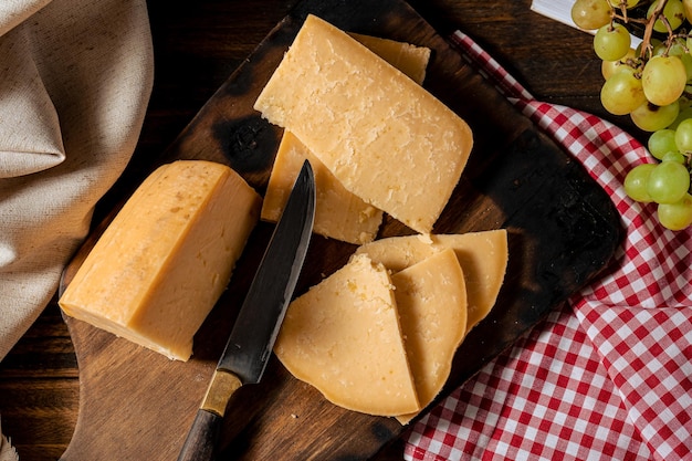 Stück von einem letzten italienischen Provolone-Käse und frisch geschnittenen Fetas auf dem Brett. Ansicht von oben.