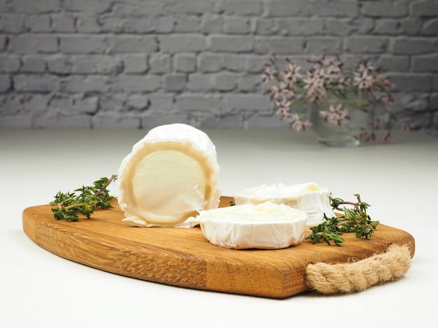 Stück Ziegenweichkäse und Thymianzweige auf weißem Hintergrund