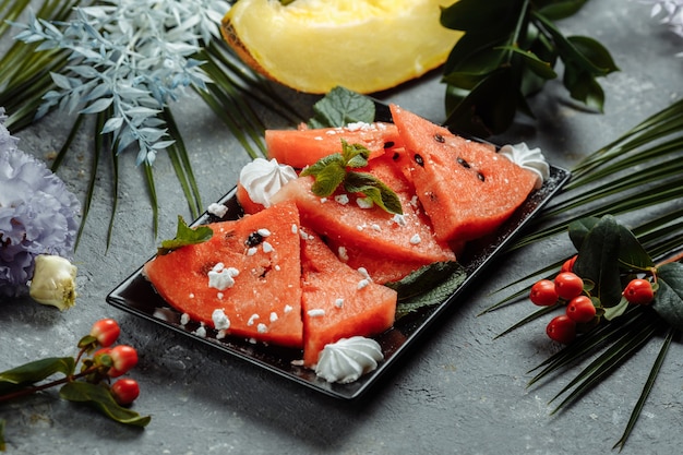 Stücke frische rote Wassermelone auf einem schwarzen Teller