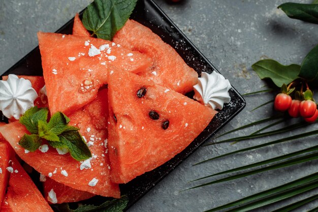 Stücke frische rote Wassermelone auf einem schwarzen Teller