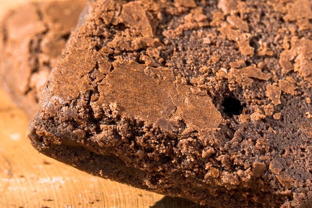 Stücke frischer Brownie auf hölzernem Hintergrund. Leckerer Schokoladenkuchen. Makro-Nahaufnahme. Selektiver Fokus.