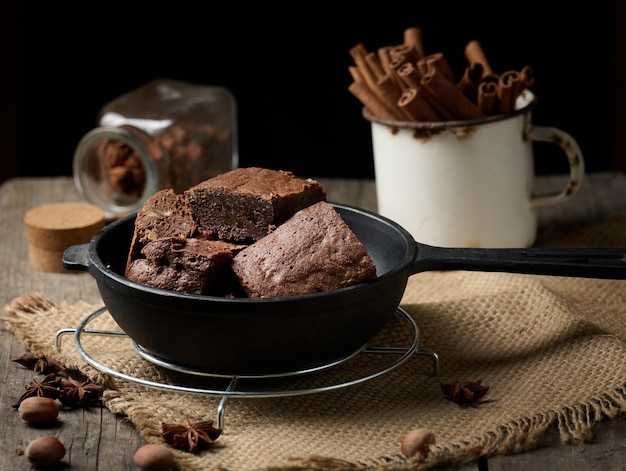 Stücke gebackener Brownie in einer schwarzen Bratpfanne aus Metall auf dem Tisch