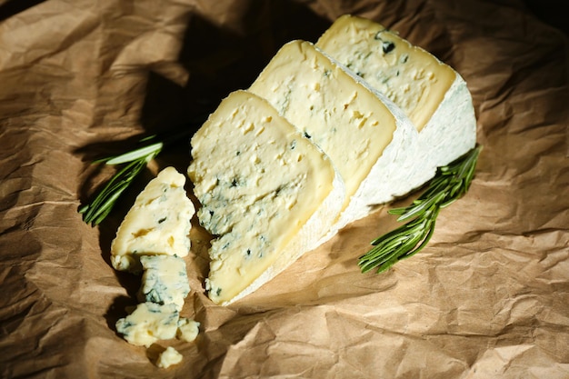 Stücke leckerer Blauschimmelkäse mit Rosmarin auf Papierhintergrund