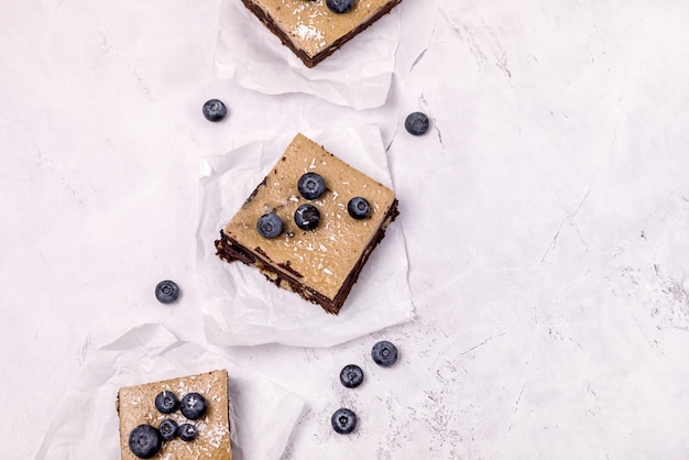 Stücke von hausgemachten Schokoladenbrownies mit reifen Blaubeeren auf grauem Hintergrund