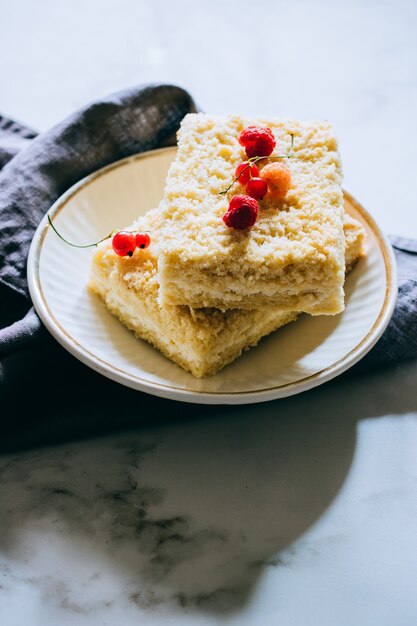 Stücke von Hüttenkäsekuchen mit einem Krümel verziert mit Himbeeren und roten Johannisbeeren