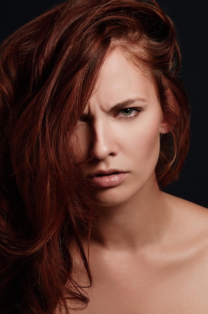 Stürmische Verführerin Closeup Portrait einer attraktiven jungen Rothaarigen im Studio finster in die Kamera blickt