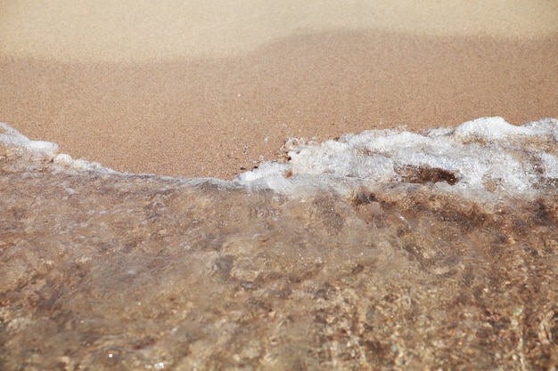 Stürmischer Seehintergrund Wellen und spritzt Sandiger Strand.