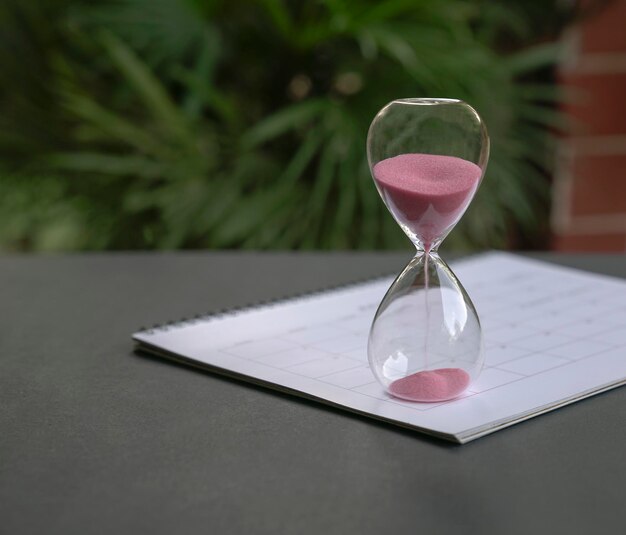 Stundenglas mit dem fließenden Sitzen des Sandes auf Kalender