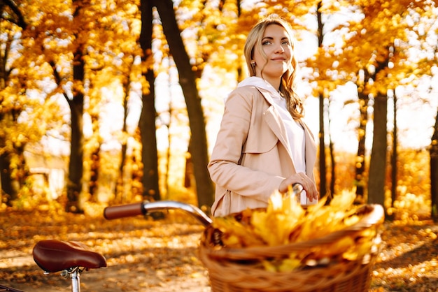 Stylische Frau mit Fahrrad genießt das Herbstwetter im Park Schöne Frau im Herbstwald