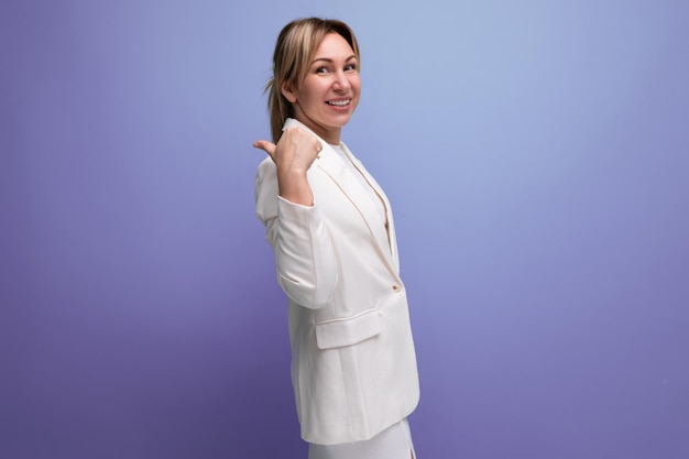 Stylische junge blonde Bürofrau in weißer Jacke auf Studio-Hintergrund mit Kopierplatz
