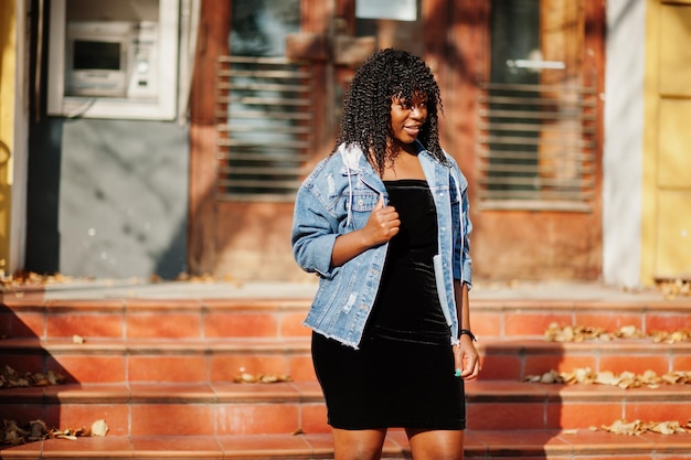 Stylische, trendige, lockige Afro-Frankreich-Frau posierte am Herbsttag in Jeansjacke Schwarzafrikanisches weibliches Modell