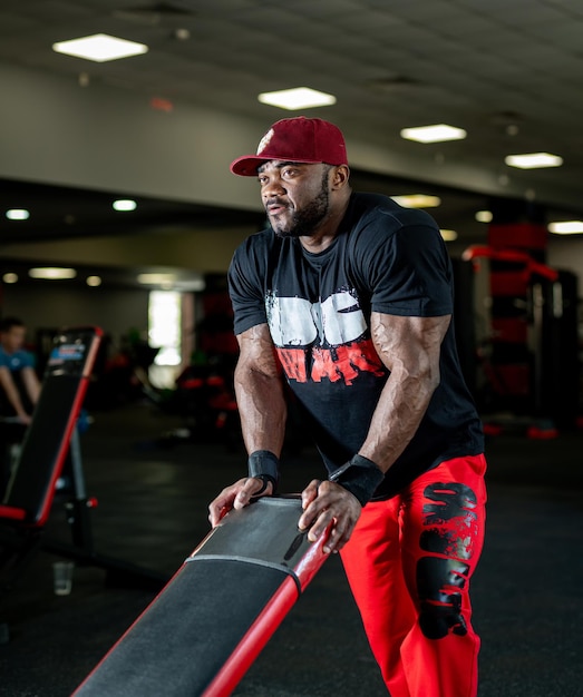 Stylischer, athletischer Mann mit hart arbeitenden Muskeln. Starker muskulöser Mann im Mützentraining im Fitnessstudio.