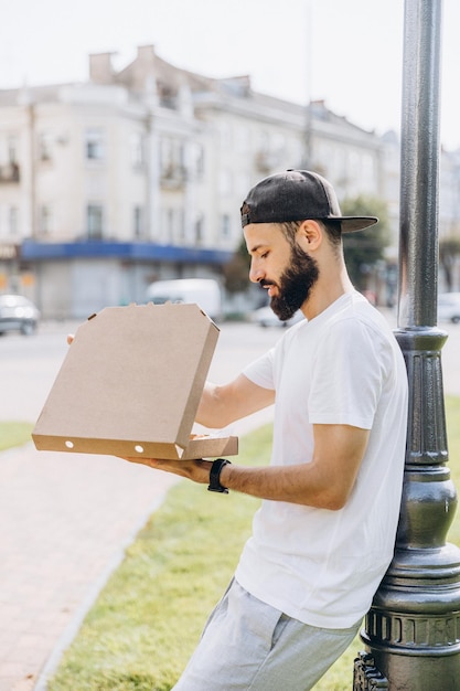 Stylischer bärtiger Mann mit einem Pizzakarton unter Ihrem Text oder Logo