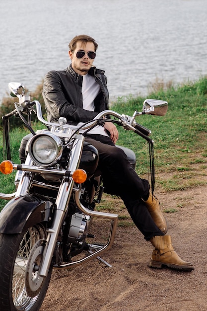 Stylischer, gutaussehender Biker sitzt und chillt auf seinem Motorrad im Freien
