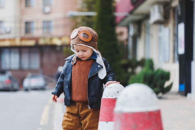 Stylischer Junge 3 Jahre alt in Lederjacke und brauner Hose geht auf der Straße Modernes Kind Kindermode Glückliches Kind