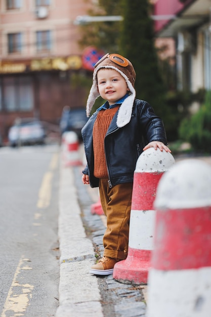 Stylischer Junge 3 Jahre alt in Lederjacke und brauner Hose geht auf der Straße Modernes Kind Kindermode Glückliches Kind