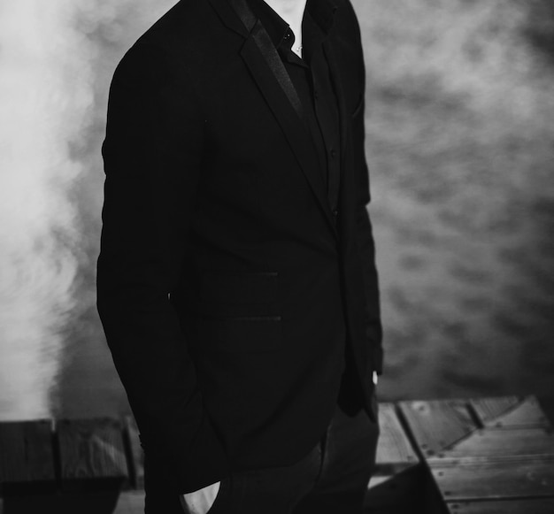 Stylischer Mann im schwarzen Anzug und posiert im modischen Kerl der Stadt