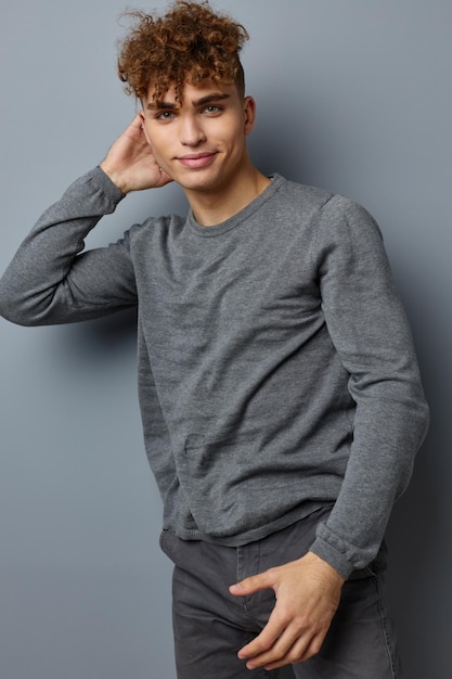 Stylischer Typ in einem grauen Sweatshirt Modestudio grauer Hintergrund