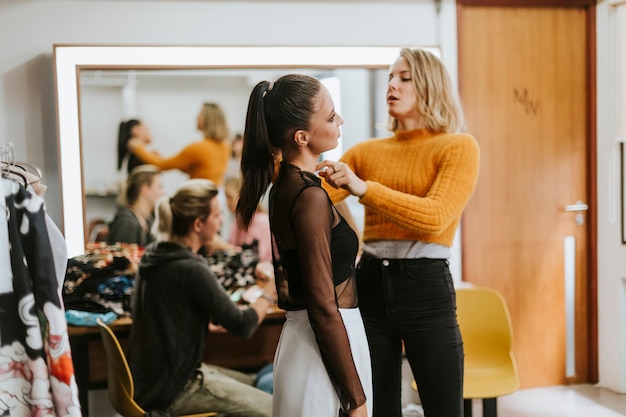 Stylist, der dem Modell hilft, sich zu verkleiden