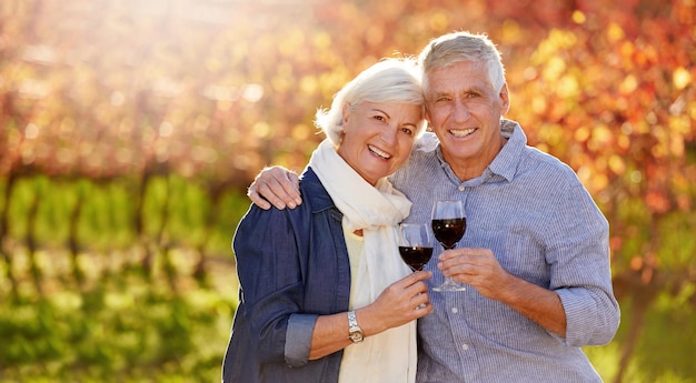 Su amor es como un buen vino Retrato de una pareja senior sonriente haciendo un brindis juntos frente a un viñedo en otoño