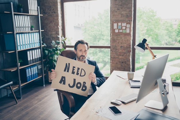 Su deprimió finanzas especialista en ventas de seguros economista abogado corporativo socio líder chico sosteniendo en las manos anuncio anuncio buscando trabajo en la moderna estación de trabajo de lugar de trabajo industrial de ladrillo loft