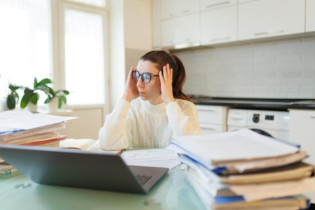 Foto en su entorno doméstico una mujer con gafas toma un descanso de su trabajo la fatiga evidente de