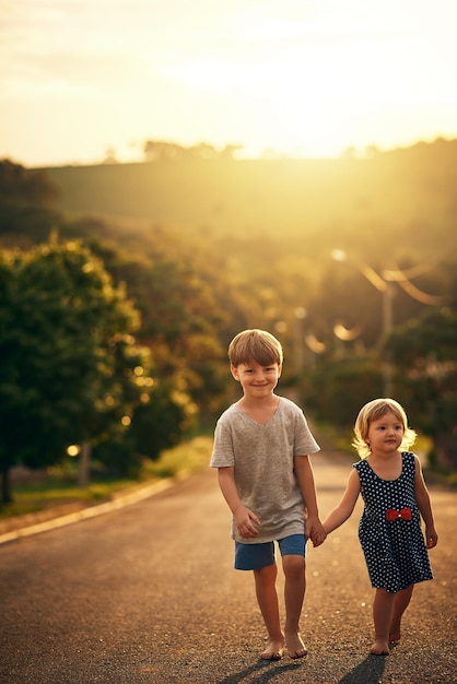 Su hermano mayor siempre la acompaña a donde quiera que vaya Fotografía de un adorable hermanito y una hermanita paseando juntos por la calle afuera