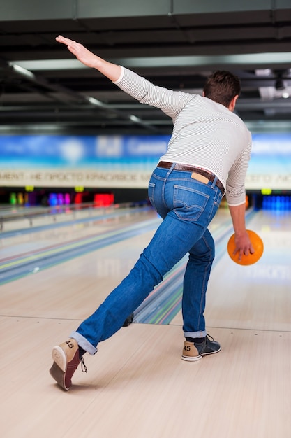 Su juego perfecto. Vista trasera del joven jugando a los bolos