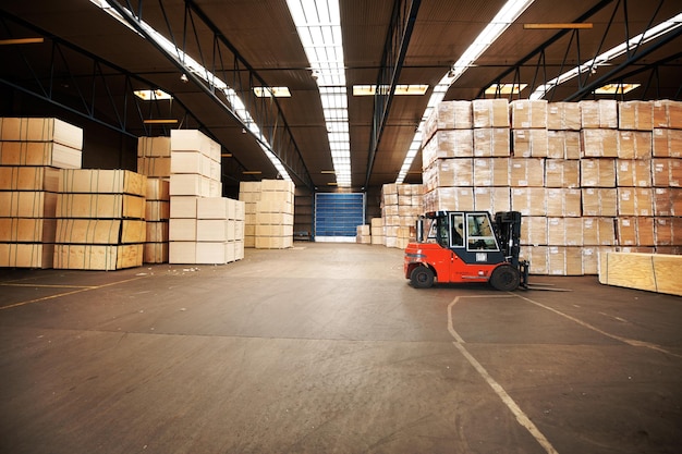 Su mercancía estará en un lugar seguro. Un gran almacén almacenando grandes cajas con una carretilla elevadora.