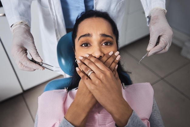 Su negocio como de costumbre hasta que sacan las herramientas Fotografía de una mujer joven que parece asustada mientras se hace un trabajo dental en los dientes