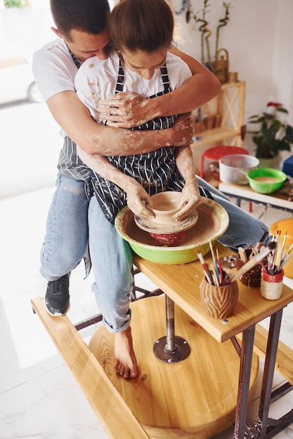 Con su novio o esposo Joven ceramista en interiores con productos de arcilla hechos a mano Concepción de la cerámica