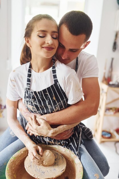 Con su novio o esposo Joven ceramista en interiores con productos de arcilla hechos a mano Concepción de la cerámica