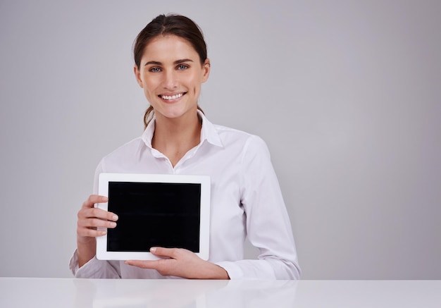 Su presencia en línea es importante Retrato de estudio de una mujer joven y atractiva que sostiene una tableta digital en blanco