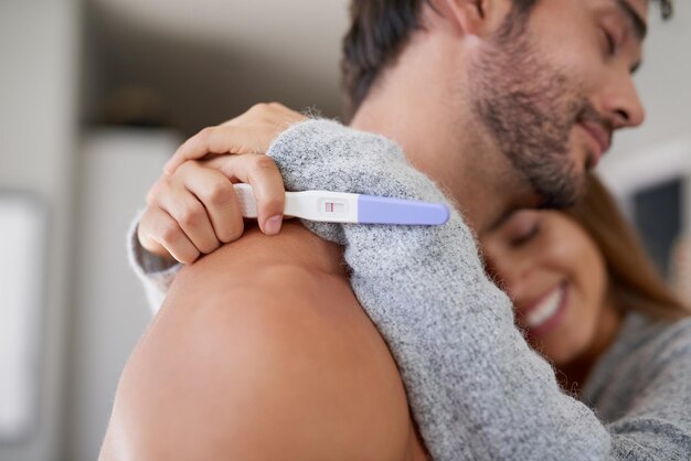 Su sueño finalmente se hizo realidad Fotografía de una joven pareja feliz abrazándose después de hacerse una prueba de embarazo en casa