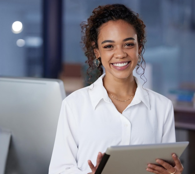 Su tableta la ayuda mucho Foto de una joven empresaria usando una tableta digital en el trabajo