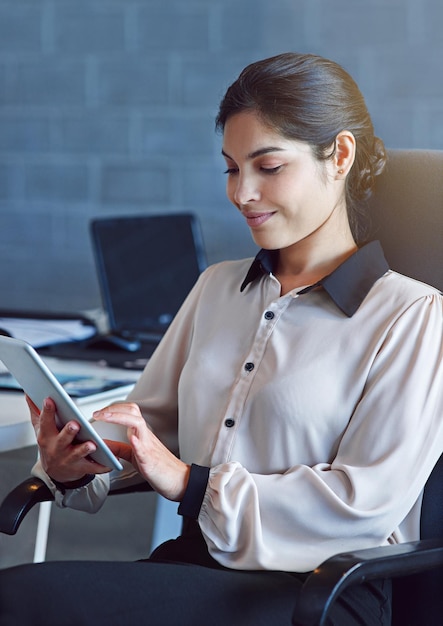 Su trabajo Captura de una joven empresaria usando una tableta digital en el trabajo