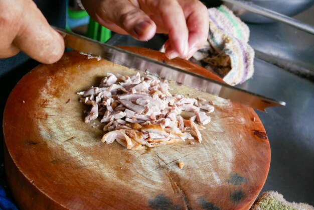 Sua carne de pato em uma tábua de corte de madeira A carne é cortada em pedaços pequenos para ser preparada para cozinhar