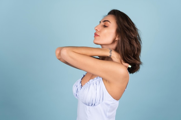 Suave retrato de una mujer joven con un vestido de peignoir azul, con el pelo rizado cayendo sobre sus hombros y un maquillaje sexy natural claro