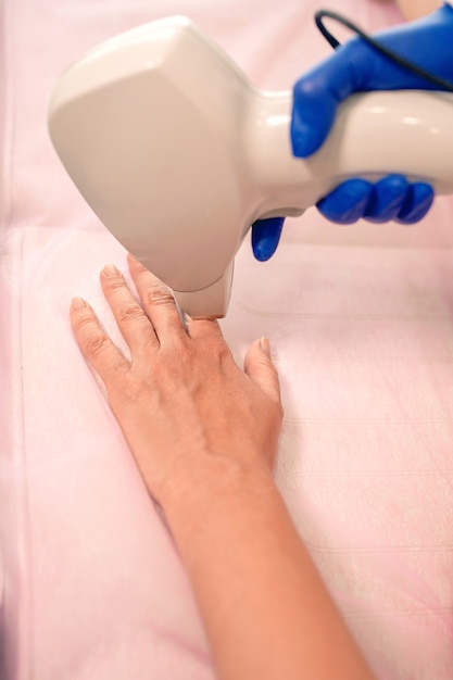 suaves dedos das mãos da mulher durante a depilação a laser no fundo do consultório de cosmetologistas