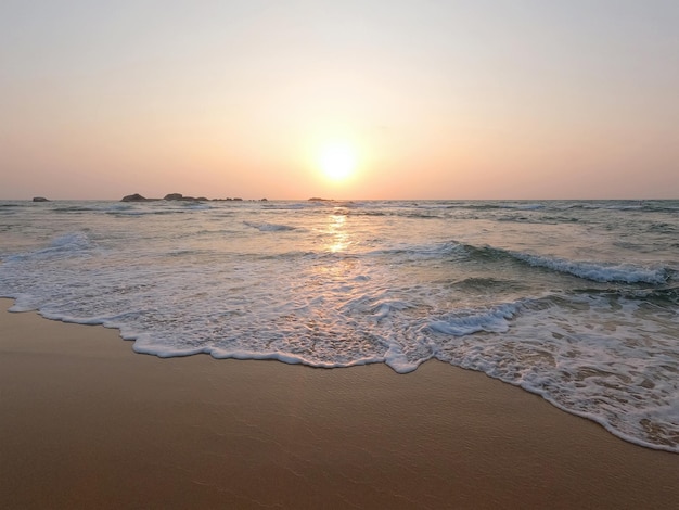 Suaves olas azules del océano en una playa de arena limpia al atardecer